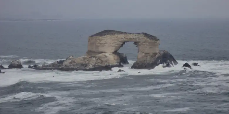 El arco de roca La Portada emergiendo del mar frente a los acantilados de Antofagasta